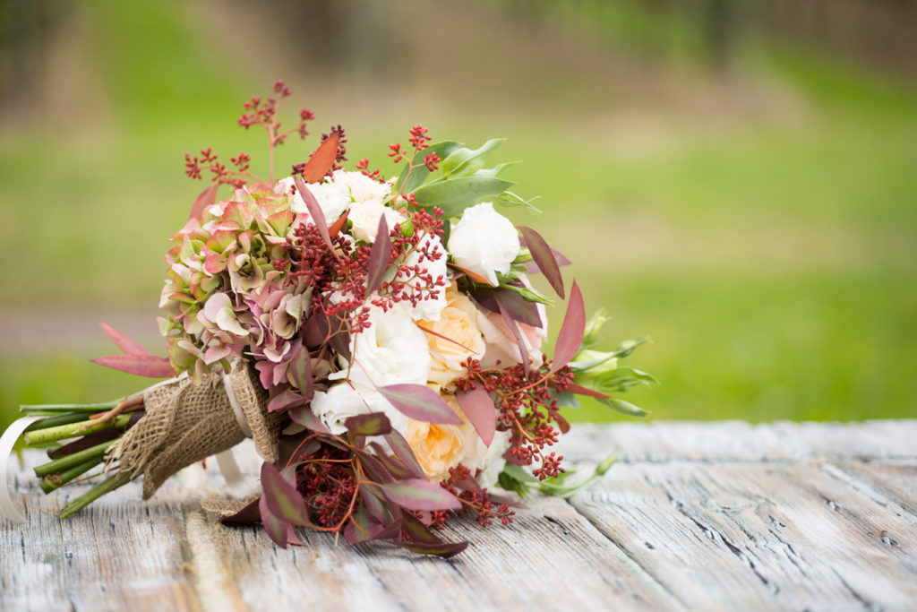 bouquet della sposa con rose e ortensie adagiato su tavolo in legno