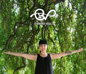 cantante cristina verderio in canotta nera che apre le braccia con sfondo i rami cascanti di un grande albero verde